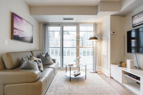 a living room with a couch and a glass table at Jarvis Suites in Toronto