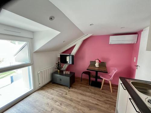 Habitación con mesa y pared de color rosa. en Joli appartement 10min ST et Soitec 5 min du touvet, en La Terrasse