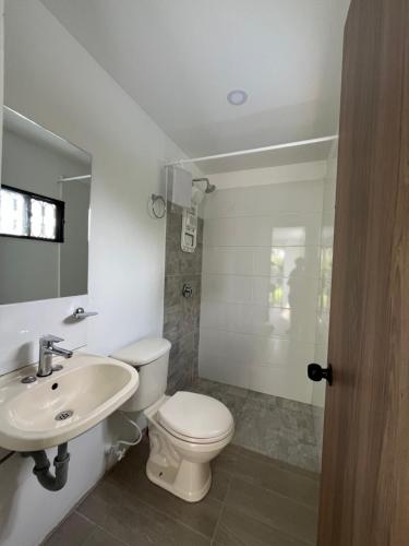 La salle de bains est pourvue de toilettes blanches et d'un lavabo. dans l'établissement Casa El Guadual, à La Mesa