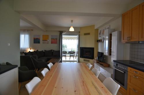 a kitchen with a wooden table and a living room at Oikia Olympus in Leptokarya