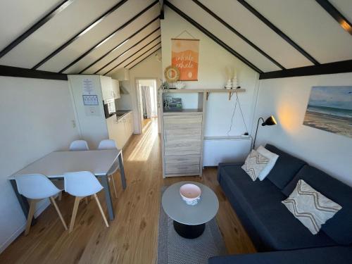 uma pequena sala de estar com um sofá e uma mesa em Appartement met prachtig polderzicht em De Haan