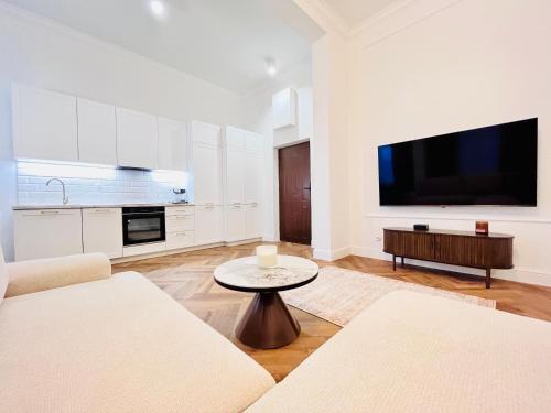 a white living room with a tv and a table at Apartamenty Lubin - Noclegi Lubin in Lubin