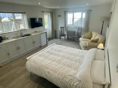a bedroom with a white bed and a living room at Large New Studio Apartment and Hot Tub - Private Hideaway in the Brecon Beacons in Bwlch