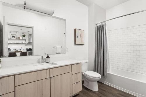 a white bathroom with a sink and a toilet at CozySuites l Chic 1BR Bottleworks Indy #5 in Indianapolis