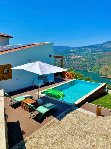 a villa with a swimming pool and an umbrella at DOURO BROTHERS in Resende