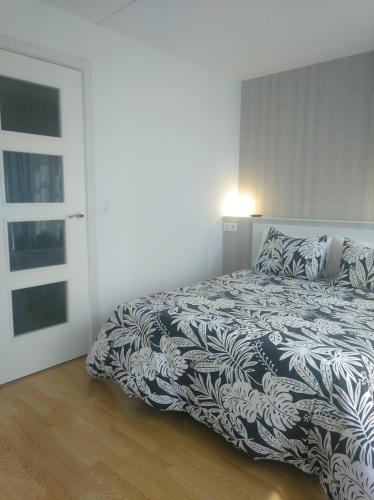 a bedroom with a bed with a black and white comforter at Estudio. Sada, A Coruña. in Sada