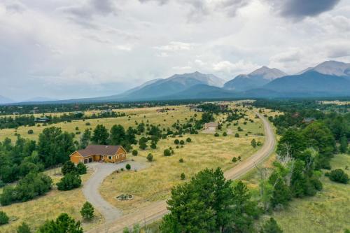 an aerial view of a house in a field with mountains at The Fox Den 360 Mtn View and On-Site Hiking! in Nathrop