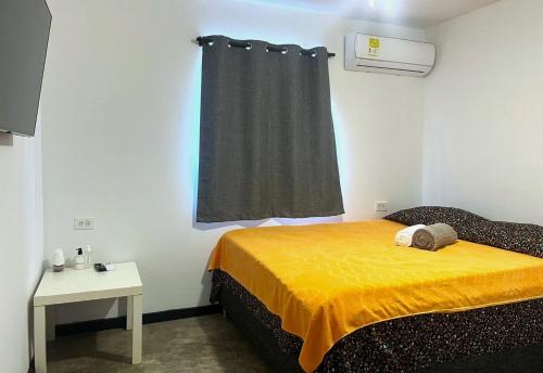 a bedroom with a bed with a yellow blanket and a window at Hotel Boutique Chateau de la Mar in Juan de Acosta