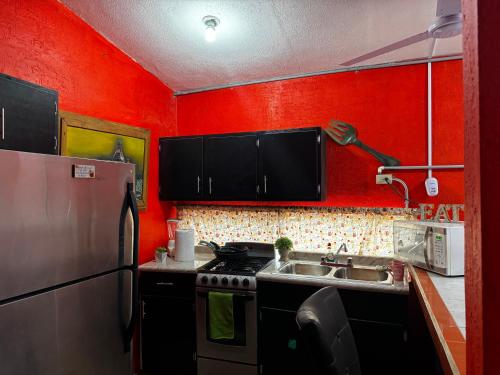 a red kitchen with a stove and a sink at Departamento Kassandra in Puerto Peñasco