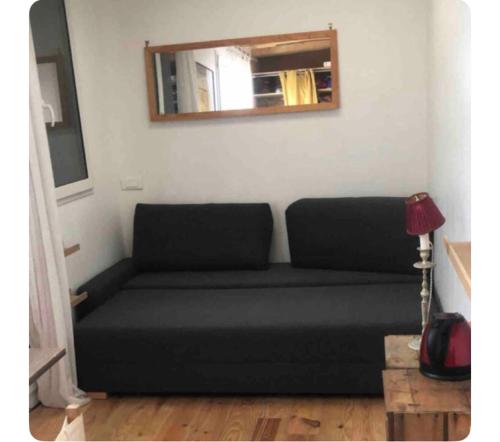 ein schwarzes Sofa im Wohnzimmer mit Spiegel in der Unterkunft Maison avec terrasse-jardin proche métro in Montreuil