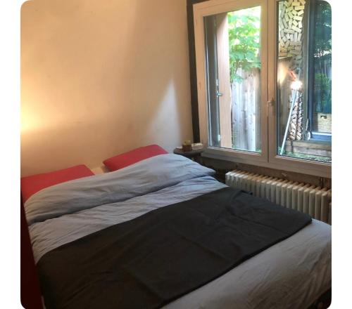 ein Bett in einem Schlafzimmer neben einem Fenster in der Unterkunft Maison avec terrasse-jardin proche métro in Montreuil