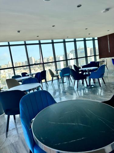a dining room with tables and chairs and windows at 2H Hotel in Oran