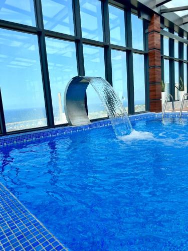a swimming pool with a fountain in a building at 2H Hotel in Oran