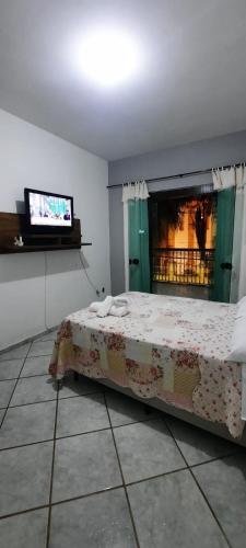 a bedroom with a bed with a fireplace and a tv at Pouso da Praça in Bonfim