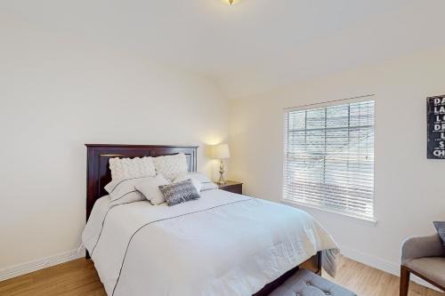 a white bedroom with a bed and a window at The Woodlands Retreat in The Woodlands