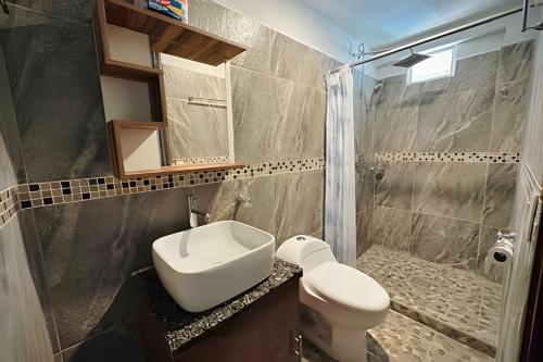 a bathroom with a sink and a toilet and a shower at Casa Las Palmas Playa La Saladita in Zihuatanejo