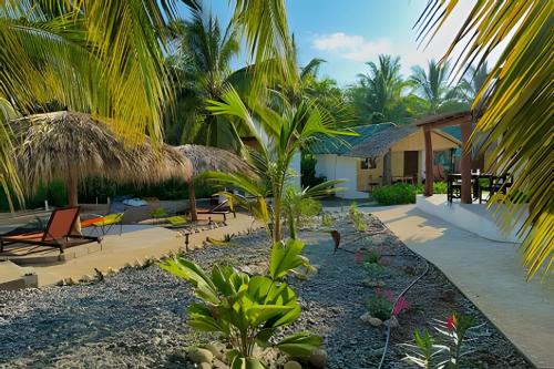 a resort with palm trees and chairs and a building at Casa Las Palmas Playa La Saladita in Zihuatanejo