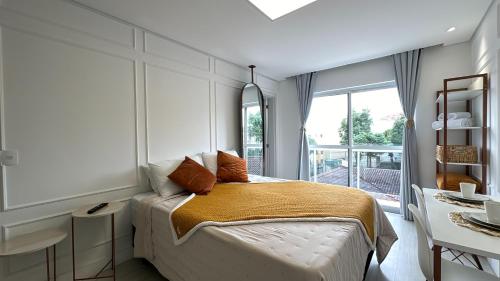 a bedroom with a bed and a large window at 23- Studio Luxo Perfeito in Curitiba