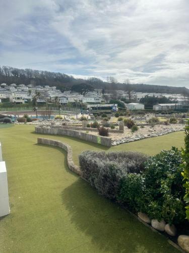 a green yard with a retaining wall and bushes at Serenity Coast in Wyke Regis
