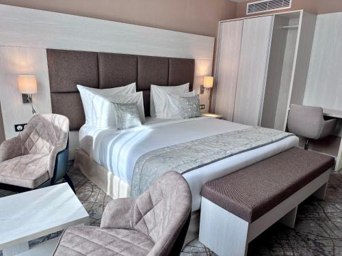 a hotel room with a large bed and two chairs at 2H Hotel in Oran