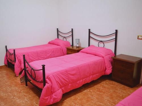 two beds with pink covers in a room at Ostello Marello in Rome