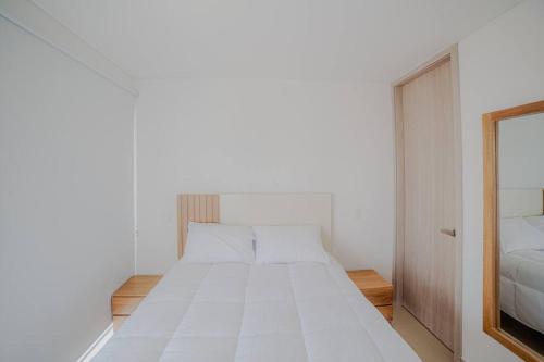 Cama blanca en habitación blanca con espejo en Altitude Haven Loft w/ Bay View, en Cartagena de Indias