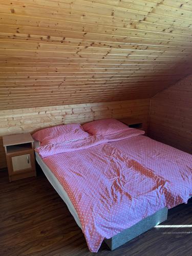 a bed in a room with a wooden ceiling at Nimród apartman in Gabčíkovo