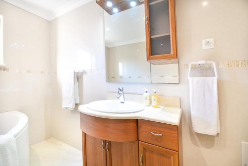 W łazience znajduje się umywalka i lustro. w obiekcie Vila com piscina a 5 minutos da Praia w mieście Alcantarilha