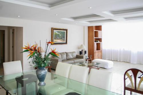 sala de estar con mesa de cristal y sillas blancas en 3 suítes Copacabana vista mar, en Río de Janeiro