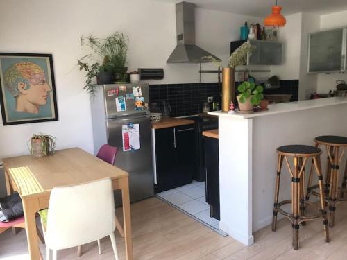 La cuisine est équipée d'un comptoir, d'une table et d'un réfrigérateur. dans l'établissement Arena Bercy JO - Paris Est - 3p lumineux terrasse, à Montreuil