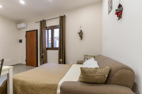1 dormitorio con cama, sofá y ventana en Appartamento Belsito 15, en Misterbianco