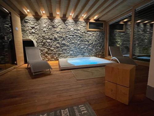 a hot tub in a room with chairs and a stone wall at Ledro Luxury Spa House in Ledro
