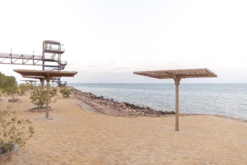 a beach with umbrellas on the sand and the ocean at La Siesta Hotel Al Sokhna in Ain Sokhna