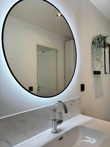 Baño con espejo redondo sobre un lavabo en Le Studio Bohème en Saint-Aignan