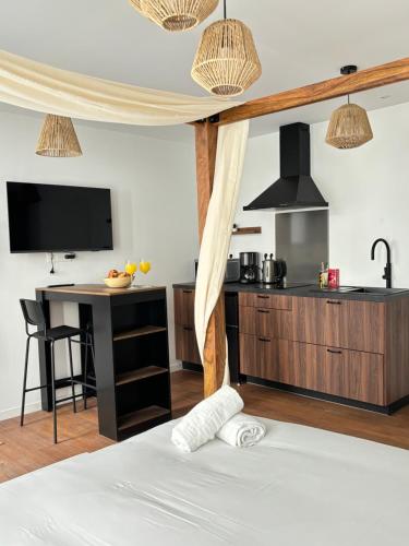 a room with a bed with a kitchen and a table at Le Studio Bohème in Saint-Aignan