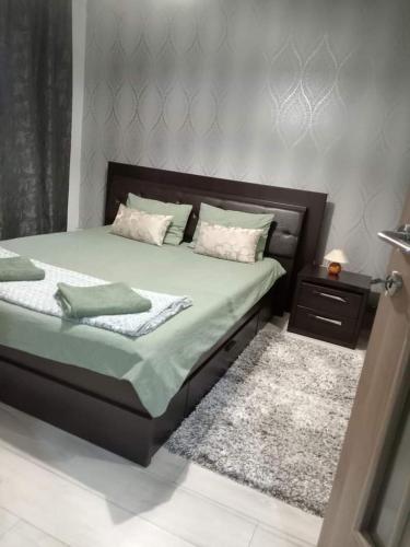 een slaapkamer met een bed en een nachtkastje met een tapijt bij NicoResident in Ocna-Mureşului