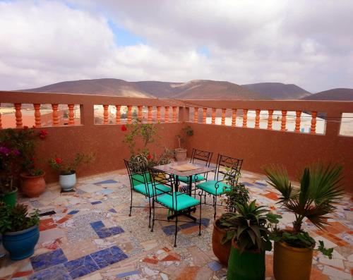 un patio con mesa y sillas con montañas en el fondo en Tayafut ApartmentTerrace, en Mirleft