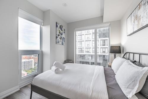 a bedroom with a white bed and two windows at Toronto Garden Apartments in Toronto