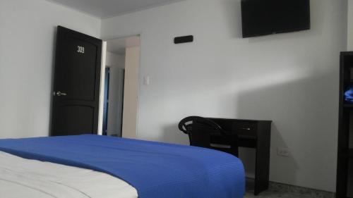 a bedroom with a bed and a desk and a television at Hotel Bucare in Yopal