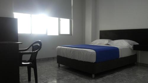 a bedroom with a bed and a desk and a chair at Hotel Bucare in Yopal
