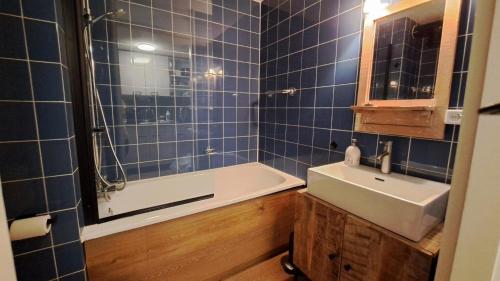 y baño con paredes de azulejos azules, lavabo y bañera. en Appartement Bru Zeeland en Bruinisse