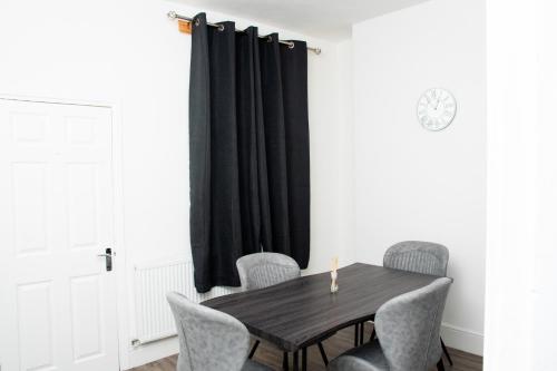 a dining room table with chairs and a black curtain at Mayfun Rooms Near Teeside Uni in Middlesbrough
