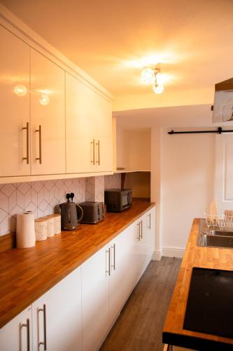 a kitchen with white cabinets and a wooden counter top at Mayfun Rooms Near Teeside Uni in Middlesbrough