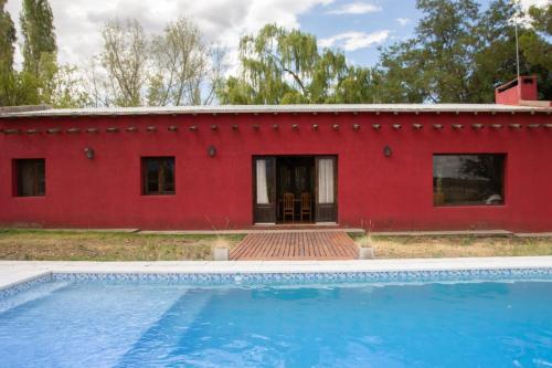 a red house with a pool in front of it at La Martina in Los Árboles