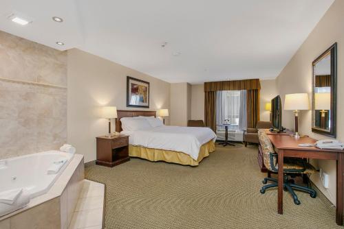 a hotel room with a bed and a desk and a tub at Holiday Inn Express & Suites Whitecourt by IHG in Whitecourt