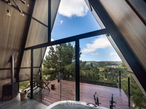 uma casa de banho com uma grande janela com vista para um deque em Chales Naturale - Campos do Jordão - CNA em Campos de Jordão