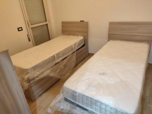 2 camas en una habitación con envolturas de plástico alrededor en HOUSE BEACH, en Borgo Sabotino