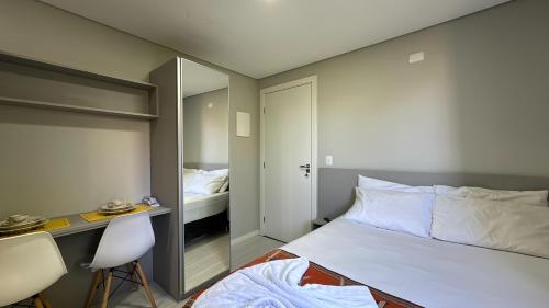 a bedroom with a bed and a desk and a mirror at 07-STUDIO ENCANTADOR PARA CASAL in Curitiba