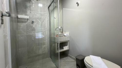 uma casa de banho com uma cabina de duche em vidro e um WC. em 07-STUDIO ENCANTADOR PARA CASAL em Curitiba