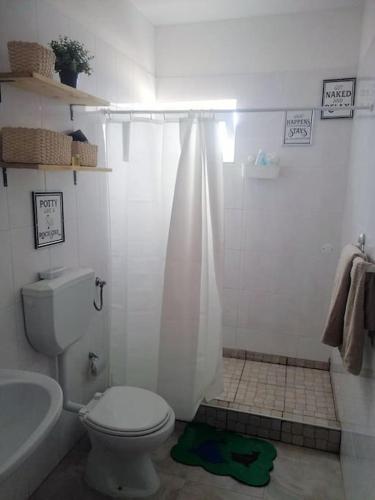 a white bathroom with a toilet and a shower at Lovely 1 Bedroom flat w/ WiFi and 5 min from beach in Santa Maria